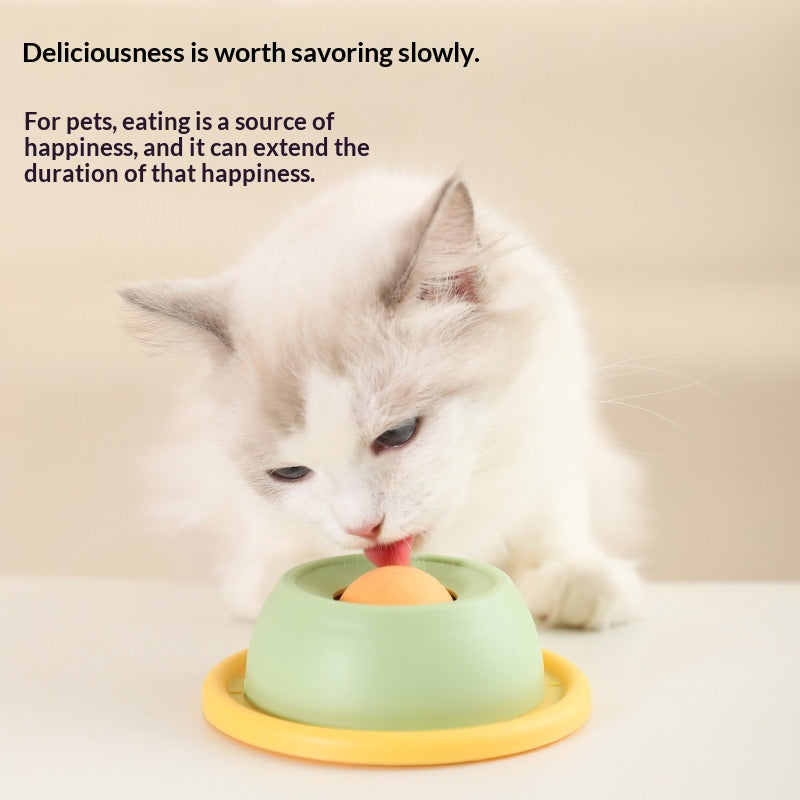 White kitten licking a treat from the green Slow Snack Lick Bowl